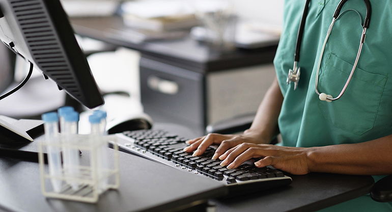 A doctor operates a computer in a medical setting